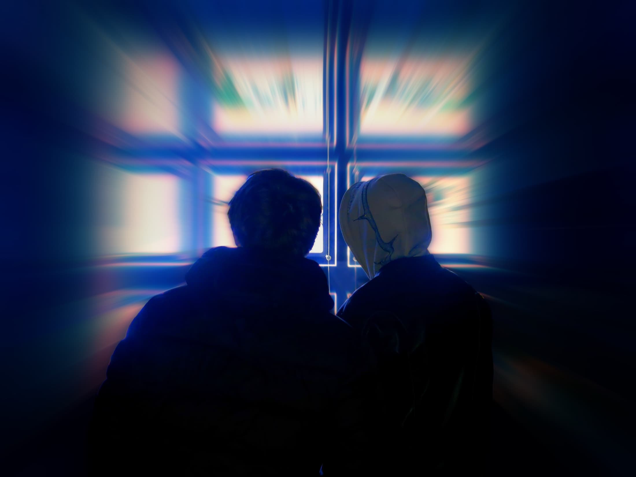 Two people silhouetted together in electric blue light, photographed by Ed Hallam