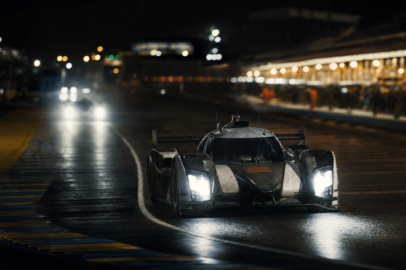 Endurance racing car driving through a wet night circuit